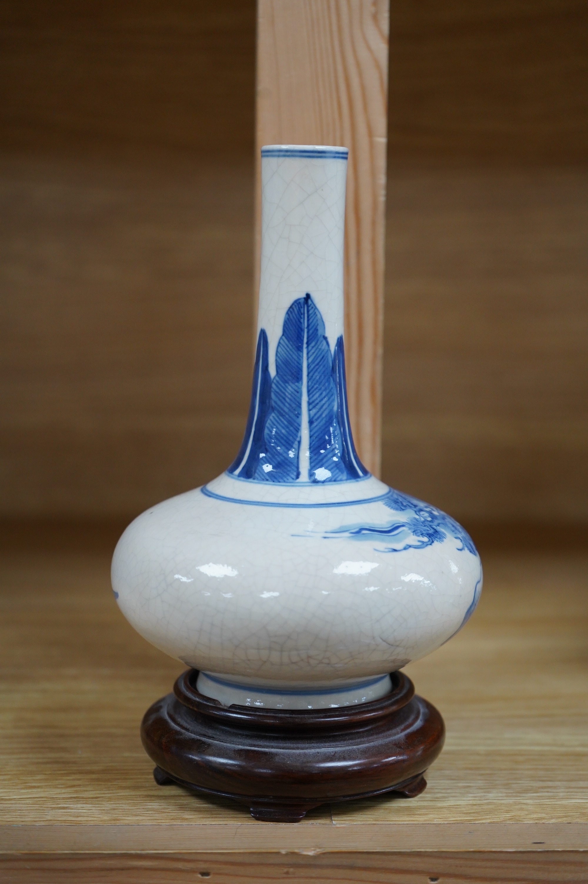 A 19th century Chinese blue and white crackle glaze bottle vase on hardwood stand, 20cm total. Condition - firing cracks to neck interior